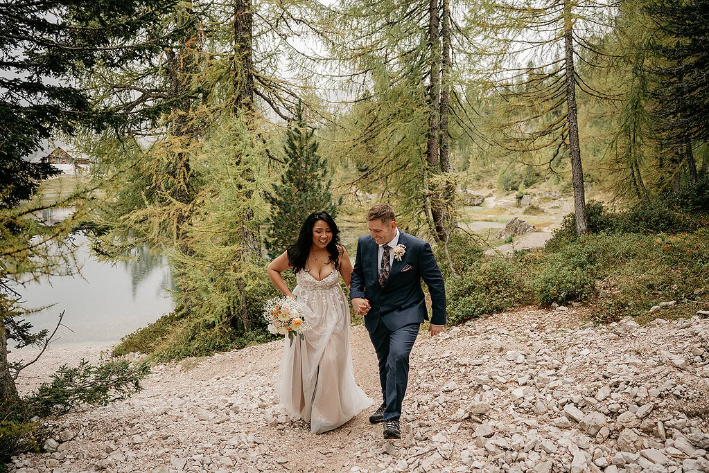 Couple walking in forest wearing wedding attire