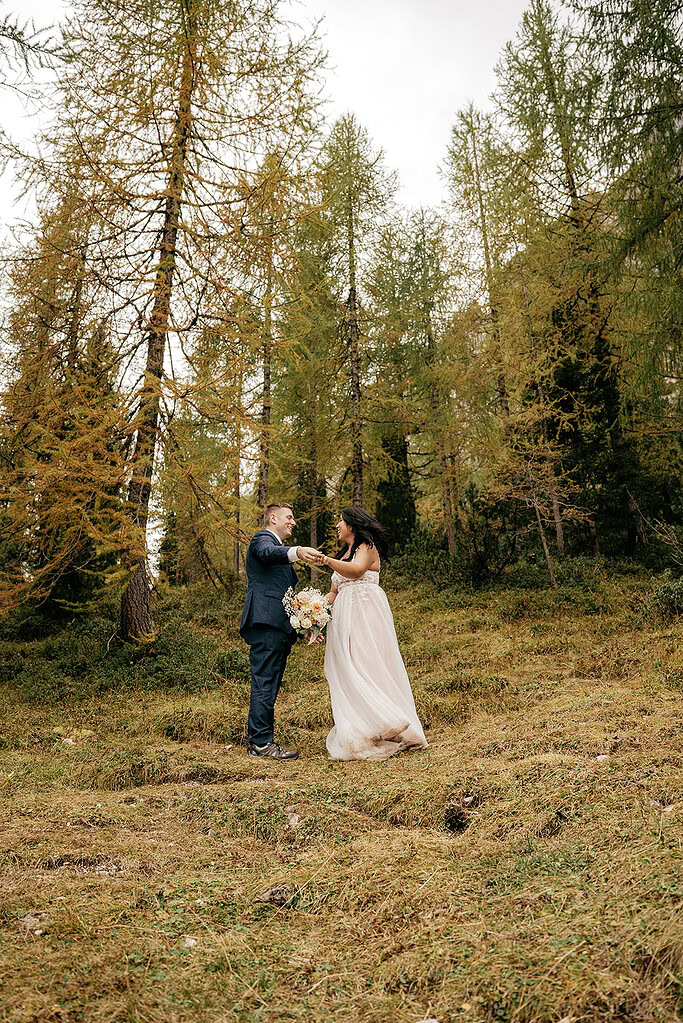 Couple holds hands in forest wedding photo