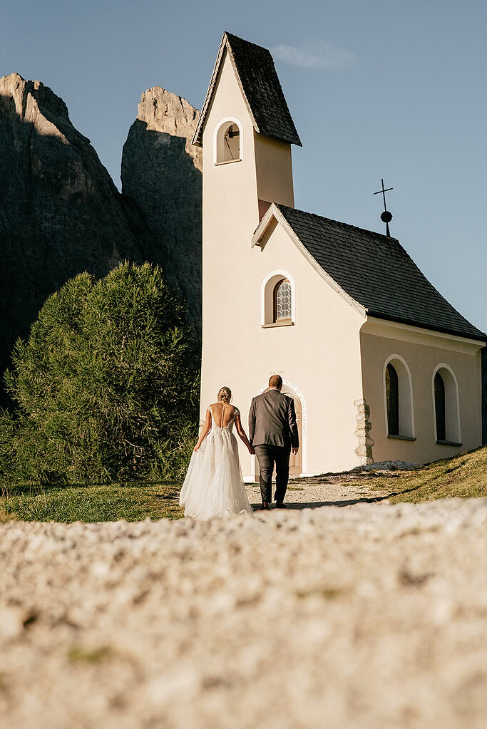 Couple walking towards small chapel in mountains