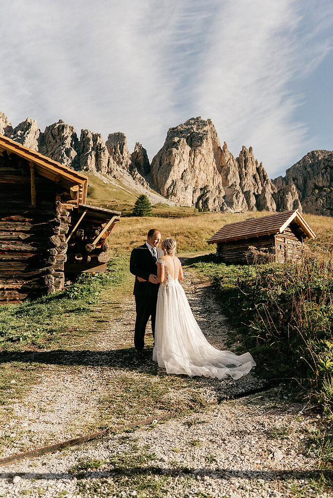 Couple in wedding attire near mountain cabins.