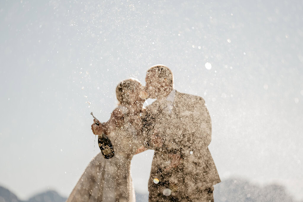 Couple kissing with champagne spray celebration.