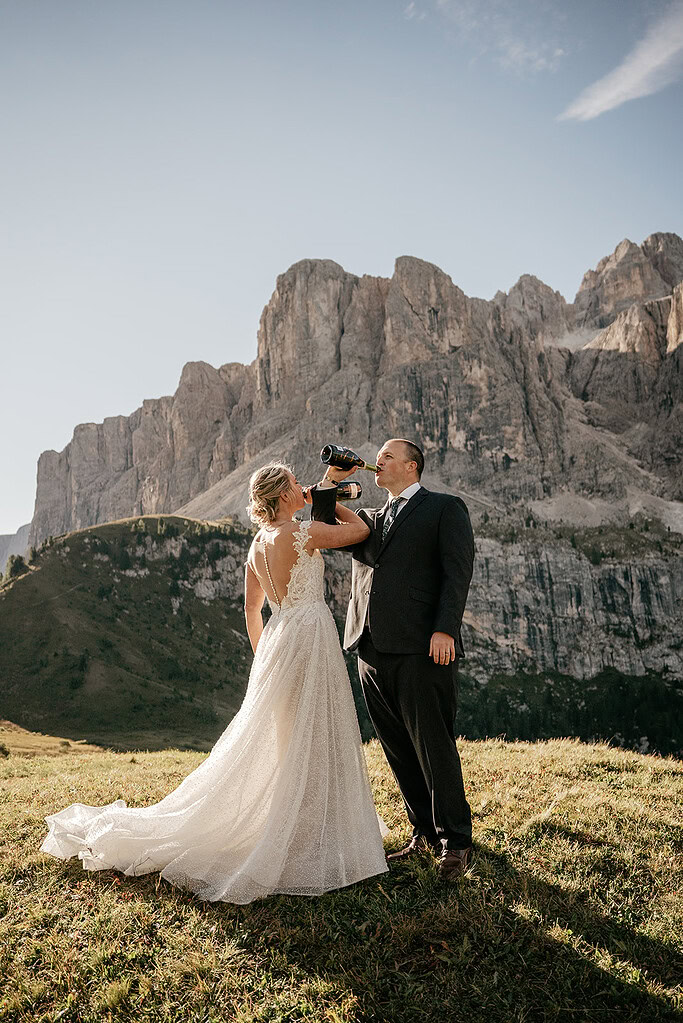 Wedding couple drinking champagne in scenic mountains.