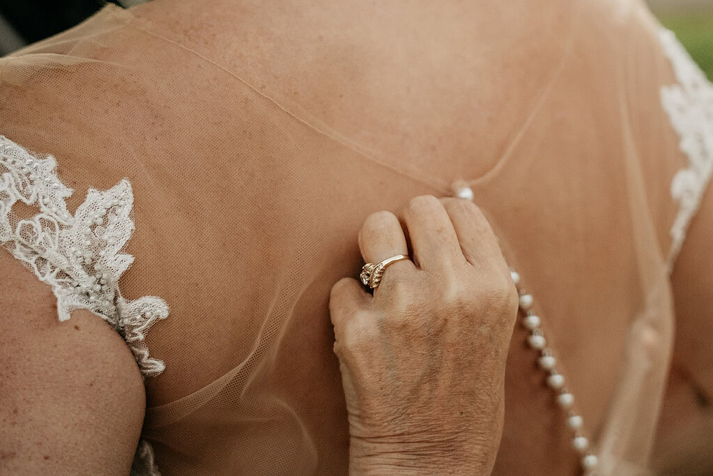 Bride holding pearl necklace on lace gown