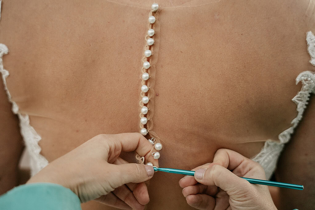 Hands buttoning pearl wedding dress back