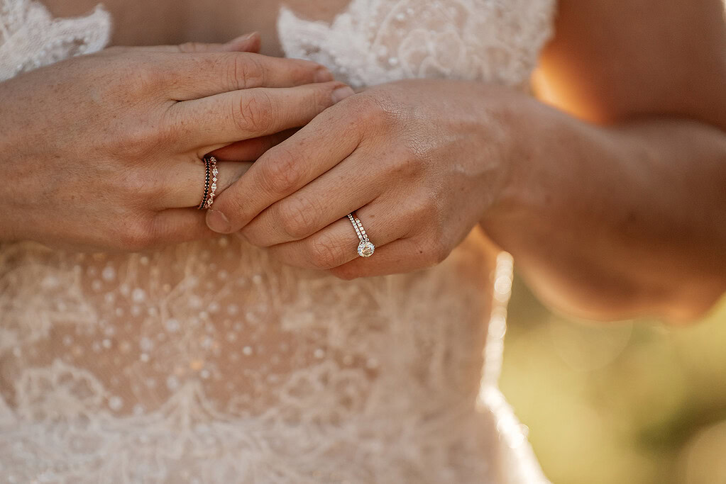 Bride with wedding and engagement rings, lace dress.