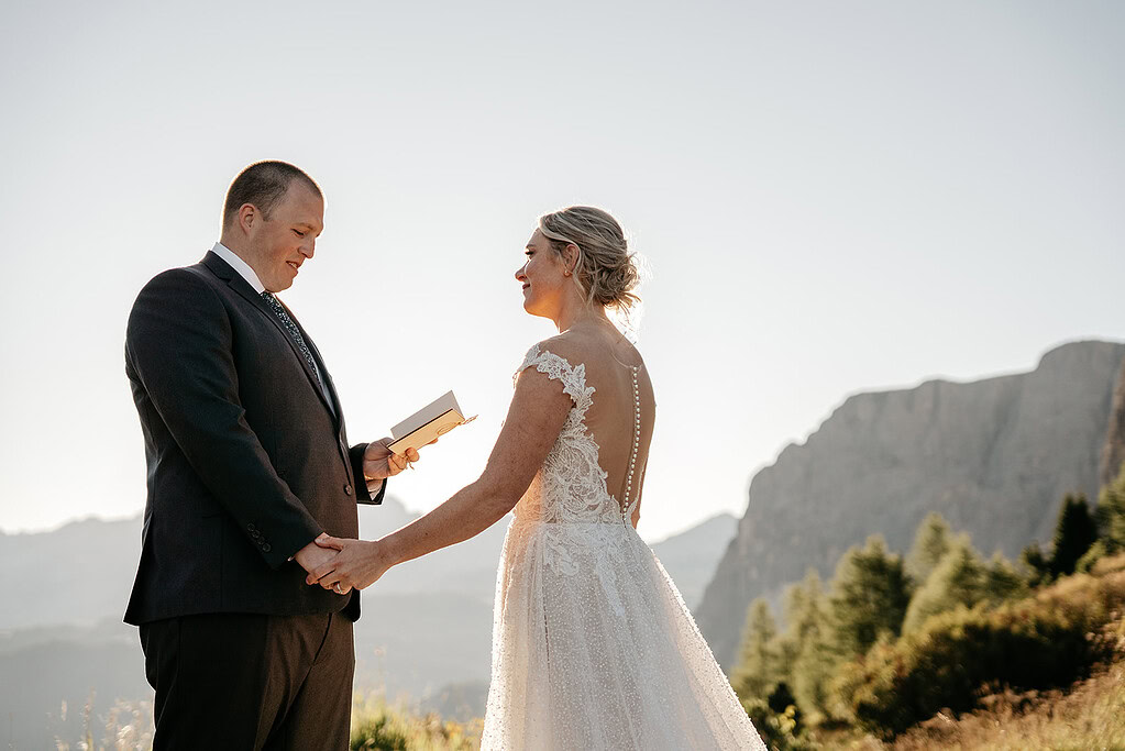 Couple exchanging vows in scenic mountain setting.