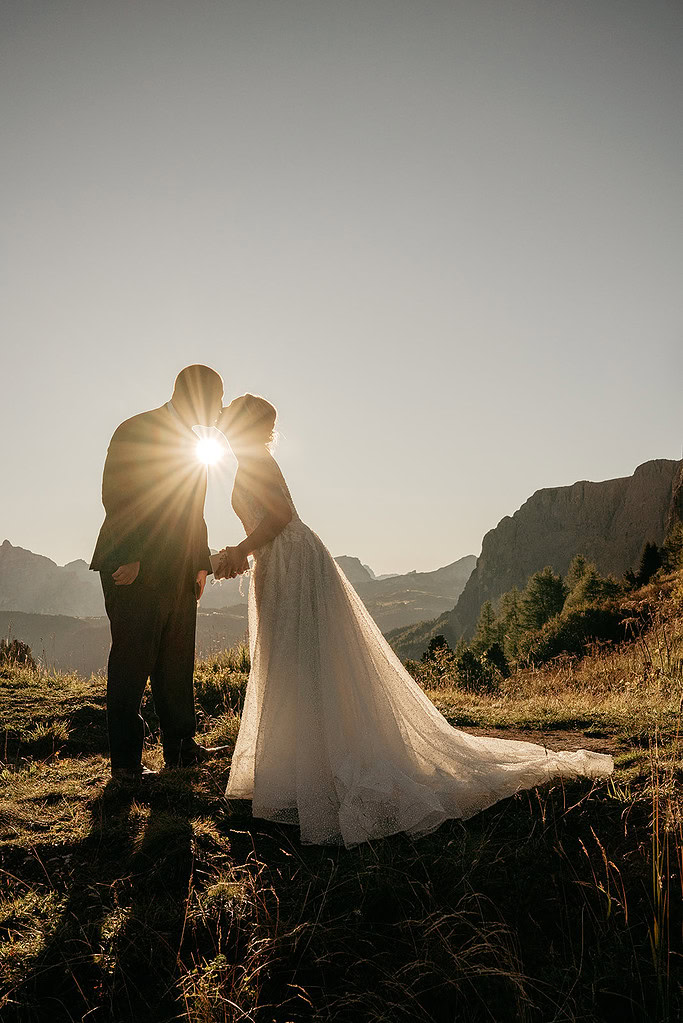 Couple kissing at sunset in mountain landscape.