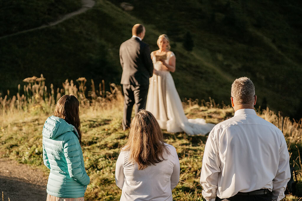 Outdoor wedding ceremony with couple and family.