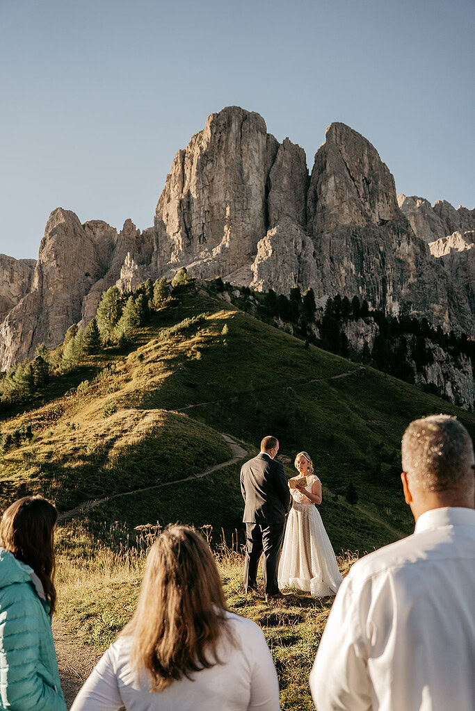 Mountain wedding ceremony with couple and guests.