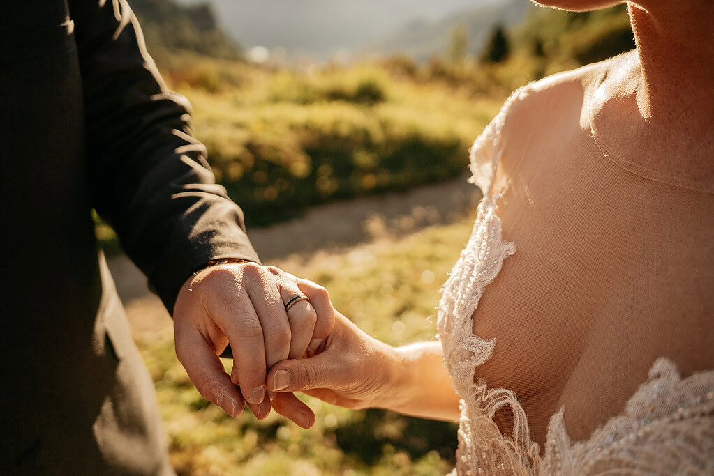 Couple holding hands outdoors during wedding ceremony.